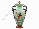 un vase vert orné d'un oiseau et contenant une cuillère