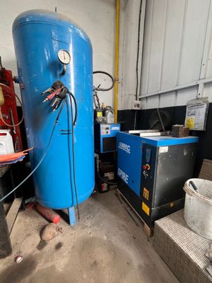 un grand réservoir bleu posé dans un garage, à côté d'autres équipements