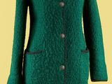 un manteau vert sur un mannequin, posé sur un fond jaune