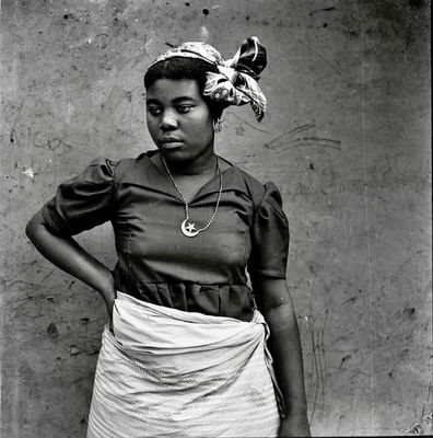 black and white photograph of a woman standing against a wall with her hands on her hips