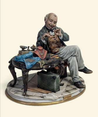 une figurine représentant un homme assis à une table avec une valise