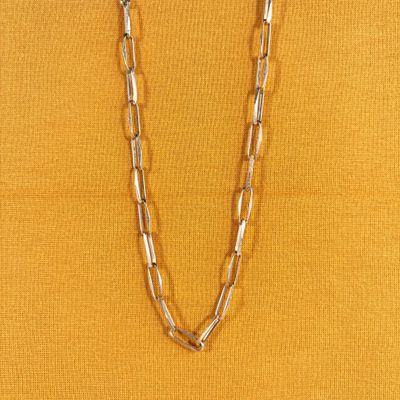 un gros plan d'une femme portant un haut jaune et un collier à longue chaîne