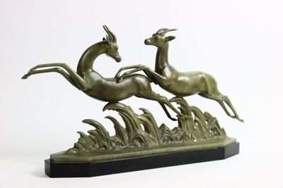 statue représentant deux cerfs en pleine course dans un champ d'herbe, sur fond blanc