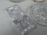 three glass ashtrays on a table next to a candle