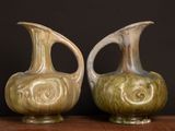 two vases sitting on a table with a black background