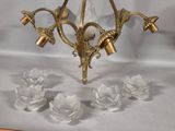 a gold chandelier with five glass flowers on it