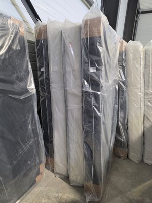 many mattresses wrapped up in plastic bags in a warehouse