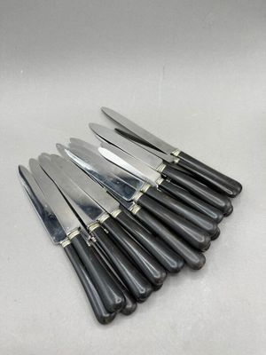 six knives are lined up in a row on a white surface