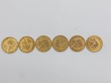 a row of five gold coins sitting on top of a white surface