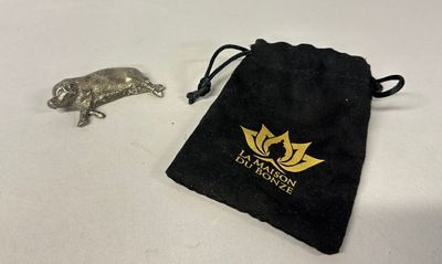 a small black bag with a gold logo next to a silver animal