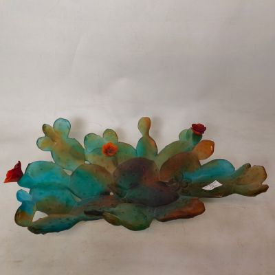 une sculpture en verre représentant un cactus posée sur une surface blanche