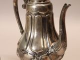 two silver teapots sitting next to each other on a table