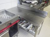 plan de travail en acier inoxydable dans une cuisine professionnelle équipée de tiroirs ouverts