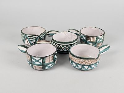 quatre tasses avec des anses et une poignée sont posées sur une table