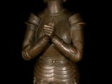 bronze statue of a woman in armor holding her hands together