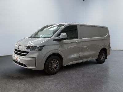La camionnette argentée est garée dans une pièce blanche au sol noir.