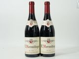 deux bouteilles de vin rouge posées l'une à côté de l'autre sur une surface blanche