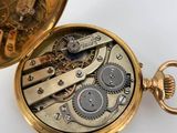 a gold pocket watch that is open on a white surface