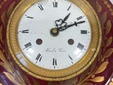 a red and gold clock that is on a wall