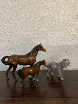 trois figurines de chevaux et un éléphant posés sur une table