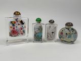 three glass bottles with different designs on them on a white surface