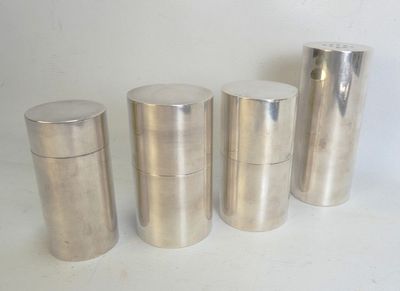 quatre récipients argentés sont alignés les uns à côté des autres sur une surface blanche
