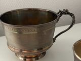 a silver cup sitting on a table next to a silver cup