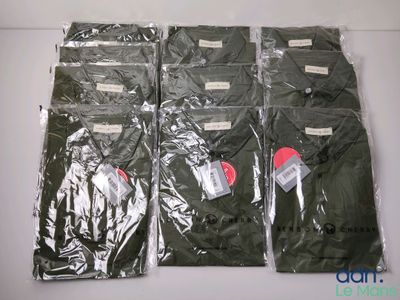 quatre t-shirts verts sont emballés dans des sacs en plastique, posés sur une surface blanche