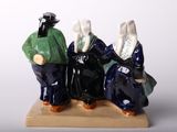 three figurines of three people sitting on a bench