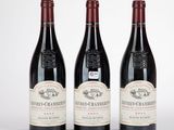 trois bouteilles de vin rouge sont alignées sur une surface blanche