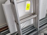 une échelle appuyée contre un mur, sur laquelle est collé un autocollant jaune
