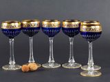 quatre verres à vin aux bords dorés, avec un bouchon posé devant chacun d'eux