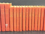 six orange books stacked on top of each other on a table