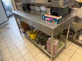 une cuisine avec une grande table en inox sur laquelle sont posés de nombreux ustensiles de cuisine
