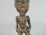 an image of a small wooden statue of a man with a cup on his head