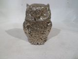 une figurine de chouette en argent posée sur une surface blanche