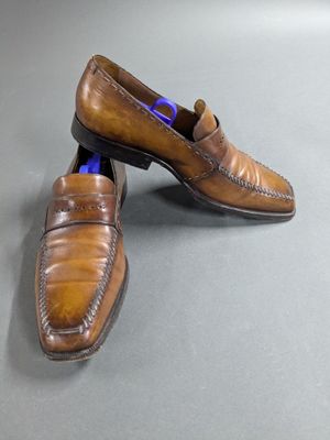pair of men ' s brown leather loafers on a gray surface