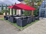 tables and chairs with red umbrellas in front of a building