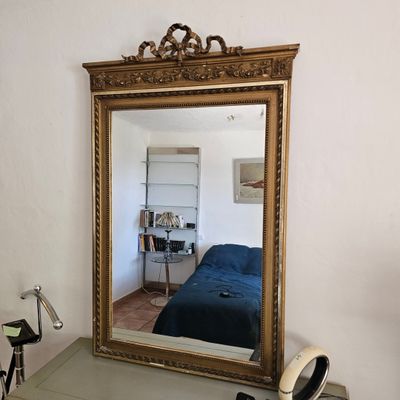 un miroir posé sur une commode, avec un lit bleu en arrière-plan