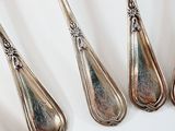 five spoons that are sitting on a white surface