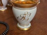 a white and gold vase with a monogram on it