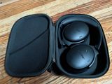 une photo représentant un casque audio dans son étui, posé sur un plancher en bois