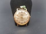 une montre-bracelet en or ornée d'une pierre verte
