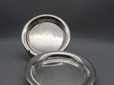 a pair of silver plated dishes on a grey background