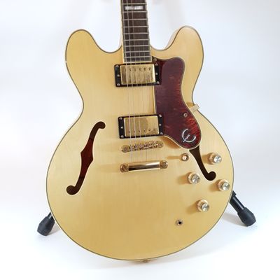 an electric guitar sitting on top of a stand on a white surface