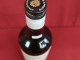 une bouteille d'alcool vide posée sur une surface rouge