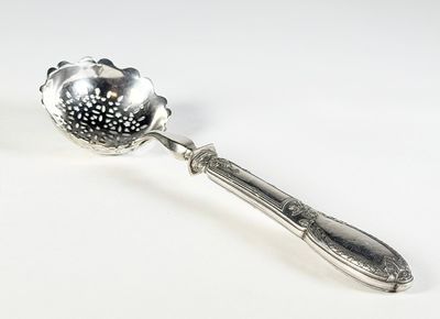 une cuillère en argent ornée d'une fleur sur une surface blanche