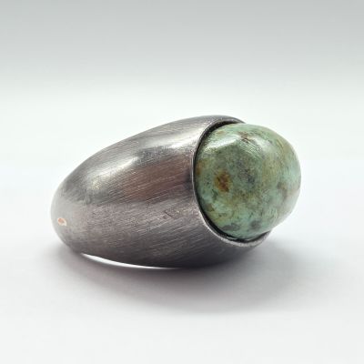 bague en argent avec une pierre verte au centre, sur un fond blanc