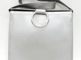 sac à main en cuir argenté muni d'une poignée en forme d'anneau métallique, sur fond blanc