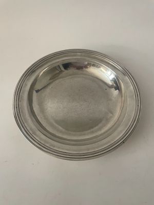 une assiette en argent posée sur une table, sur fond blanc